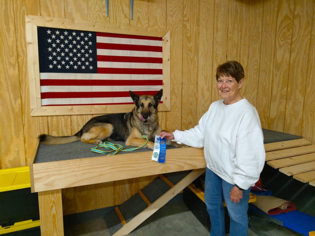 woman standing by her dog while it lays on platform