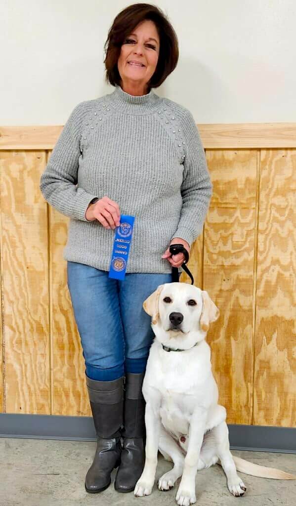 smiling woman with her dog holding a ribbon