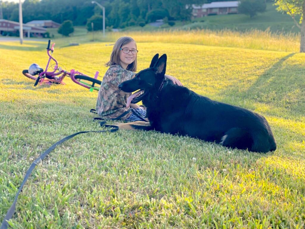 girl sitting in the grass with her dog