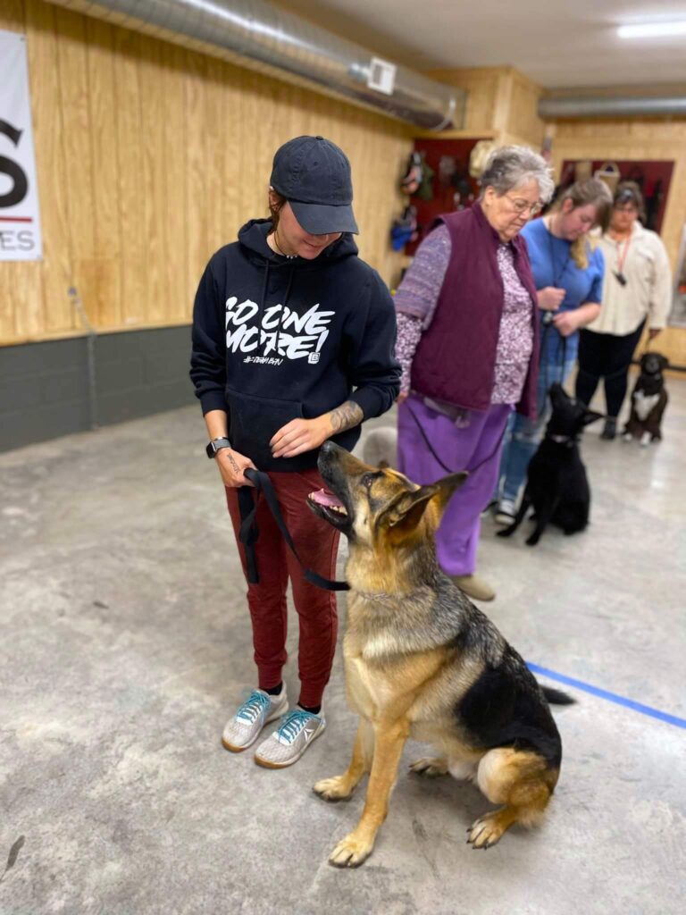 woman looking down at her sitting dog